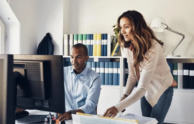 People looking with interest at computer monitor, in an office