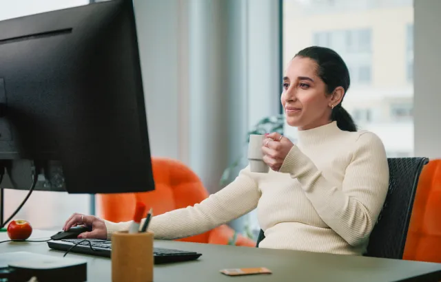 Woman drinking and working at her desk